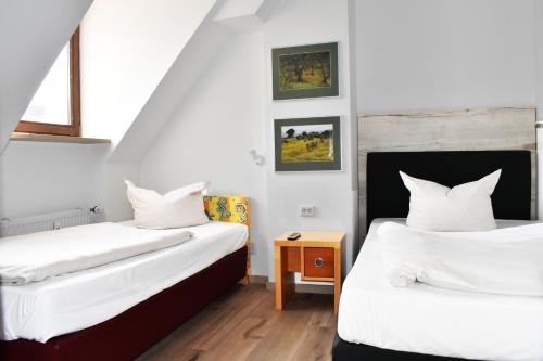 two beds in a room with white sheets at Avenon Privathotel Schwaiger Hof in Schwaig bei Nürnberg