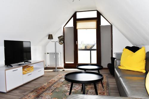 a living room with a couch and a tv at Avenon Privathotel Schwaiger Hof in Schwaig bei Nürnberg