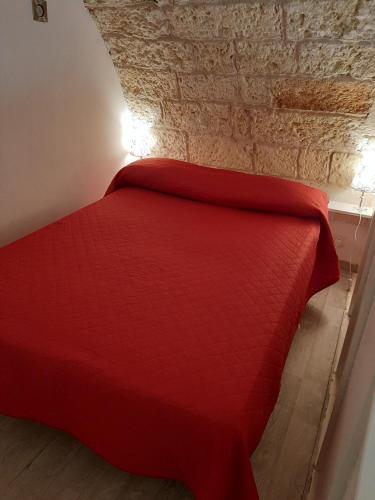 ein rotes Bett in einem Zimmer mit Ziegelwand in der Unterkunft Casa di Carmine 2 in Galatina