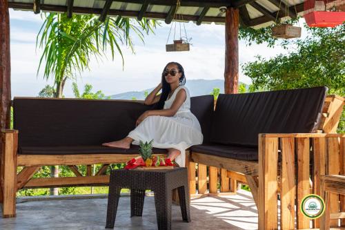 a woman in a white dress sitting on a bench at Colina Buena vista A4 in Jarabacoa
