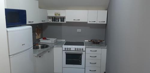 a white kitchen with a stove and a refrigerator at Stan na dan - apartman Djordjevic in Vranje