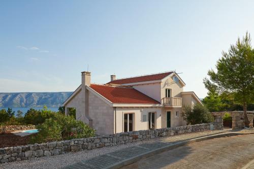 a white house with a stone wall next to a road at Hvaretta Villas in Stari Grad