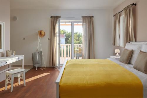 a bedroom with a yellow bed and a desk and a balcony at Hvaretta Villas in Stari Grad