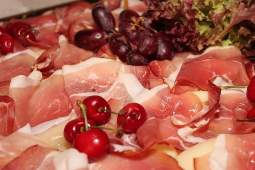 a pizza with meat and grapes on it at Hotel-Pension Waldeck in Todtmoos