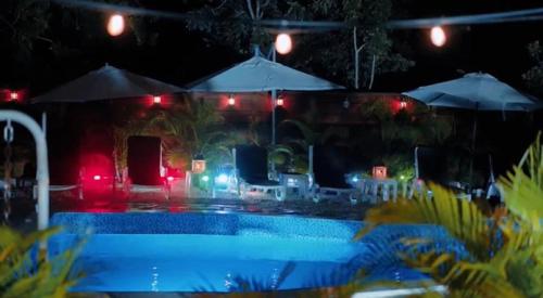 a swimming pool at night with lights and umbrellas at Colina Buena vista A4 in Jarabacoa