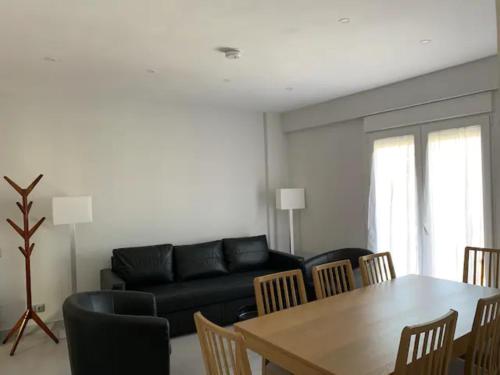 a living room with a black couch and a table and chairs at RentalSevilla Moderno apartamento en Triana de 95m2 in Seville