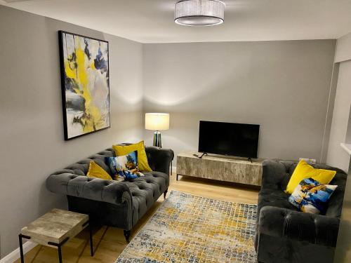 a living room with two couches and a flat screen tv at Dunlap Apartments in Strabane