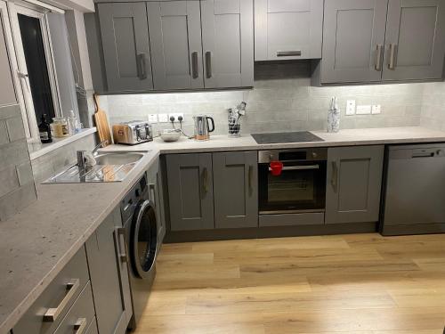 a kitchen with gray cabinets and a sink and a dishwasher at Dunlap Apartments in Strabane