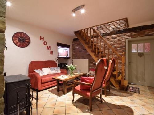 a living room with a red couch and a staircase at Restored cottage in an old Ardennes farmhouse in Nimbermont
