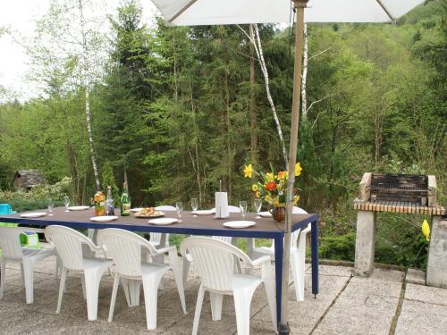 a blue table with white chairs and an umbrella at Valley View Villa in Le Menil with Private Garden in Le Ménil