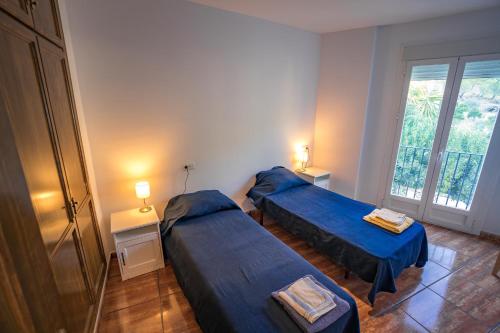 Un dormitorio con dos camas y una ventana. en Calle Cruz, en Jubrique
