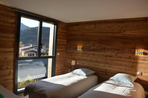 two beds in a room with a window at Chalet de charme, au calme, vue splendide, 15 personnes in Les Houches