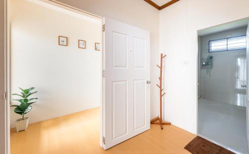 una puerta blanca abierta en una habitación blanca con una planta en Hoteru House Ranong 2 - โฮเตรุ เฮ้าส์ ระนอง, en Ranong