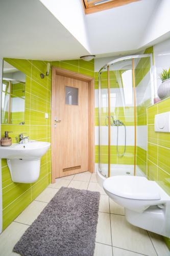 ein Badezimmer mit grün gestreiften Wänden, einem WC und einem Waschbecken in der Unterkunft Gościniec pod Lilijką in Podzamcze