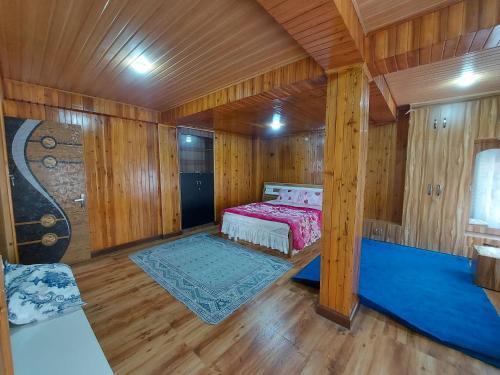 une chambre avec un lit dans une pièce en bois dans l'établissement Bitta Inn homestay, à Darjeeling