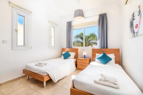 2 Betten in einem Zimmer mit 2 Fenstern in der Unterkunft Villa Oscar in Protaras