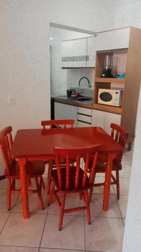 una mesa roja y sillas en una cocina en Ilha do Coral Residence, en Florianópolis