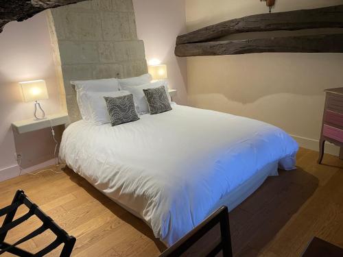 a bedroom with a large white bed with two pillows at Le Cottage d'Eleanor gîte de charme avec spa Jacuzzi privé in Marçay