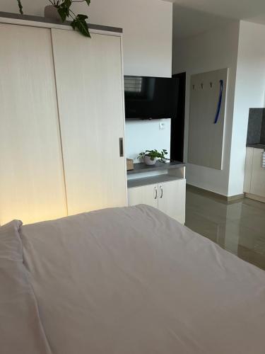a bedroom with a white bed and a kitchen at Penzion vinařství Mikulica in Velké Pavlovice