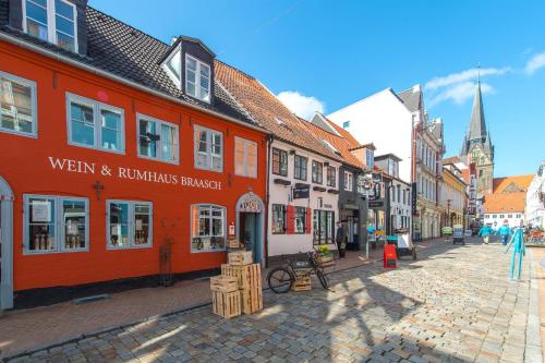 a cobblestone street in a town with orange buildings at Ferienwohnung Storchennest in Hürup
