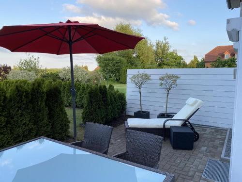 a patio with a red umbrella and chairs and a pool at Ferienwohnung Andres in Wees