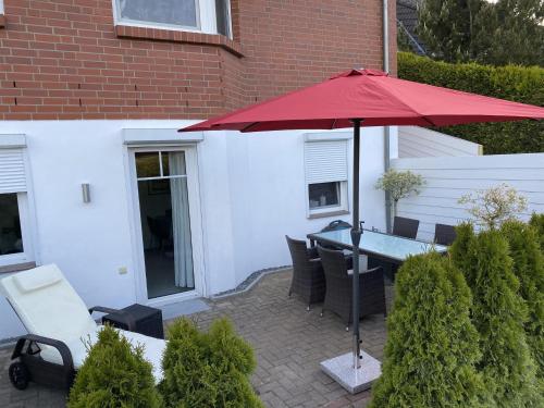 a patio with a table and a red umbrella at Ferienwohnung Andres in Wees