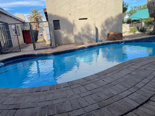 a swimming pool with blue water in front of a house at SapzRes at Klerksdorp in Klerksdorp
