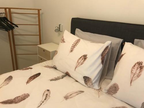 een bed met twee witte kussens met veren erop bij Quiet and cosy apartment near the city center of Diest in Diest