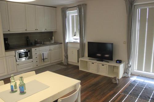 een keuken met witte kasten en een flatscreen-tv bij Appartement 660 Erik in Flensburg