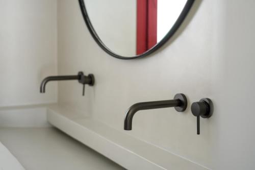 a bathroom with two faucets and a mirror at Potnia Theron Suites in Akrotiri