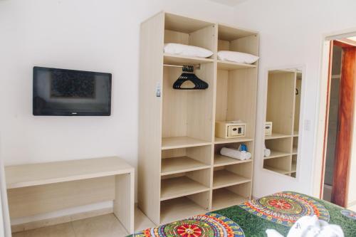 a bedroom with a bed and a tv and shelves at Jardim Atlântico Beach Resort in Ilhéus