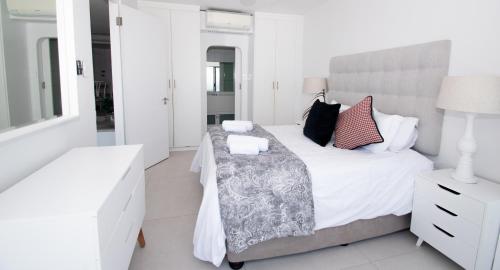 Habitación blanca con cama y espejo en 1002 Bermudas - by Stay in Umhlanga, en Durban