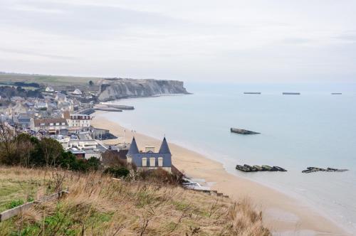 a view of a beach with houses and the ocean at Appartement proche de la plage - wifi, bien agencé in Asnelles