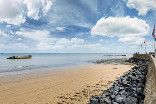 a sandy beach with a pier in the water at Appartement proche de la plage - wifi, bien agencé in Asnelles