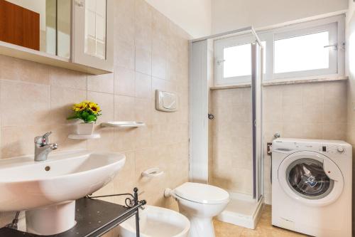 a bathroom with a sink and a washing machine at Appartamento Cristallo by BarbarHouse in Torre Lapillo