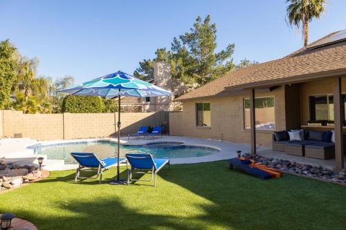 een achtertuin met een zwembad met stoelen en een parasol bij Scottsdale Friess home in Scottsdale