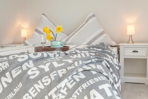 a bedroom with a bed with a gray and white comforter at Ferienwohnung - Tessa in Tinnum
