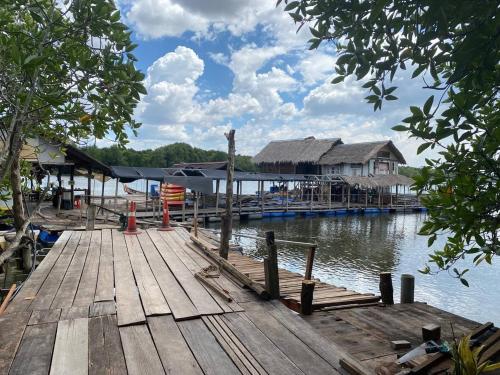 CabinStay Cikgu Sungai Batu Besi في سونغاي بيتاني: رصيف خشبي مع منزل على الماء