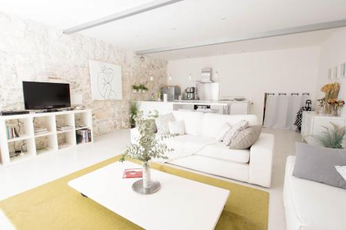 ein weißes Wohnzimmer mit einem weißen Sofa und einem Tisch in der Unterkunft Côté Arènes, Clim - Terrasse in Arles