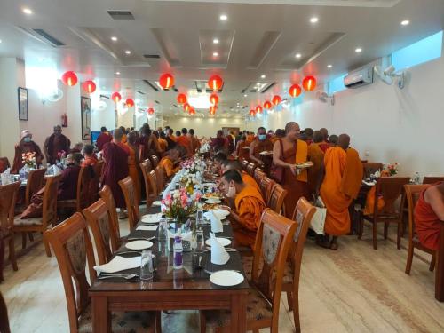 a group of monks sitting at a long table in a room at HOTEL ANAND INTERNATIONAL in Bodh Gaya