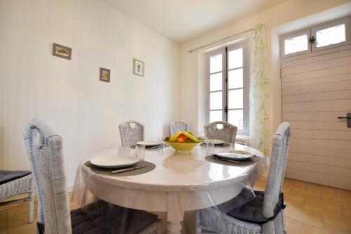 een eetkamer met een witte tafel en stoelen bij L'Oustau - ruelle bucolique in Arles