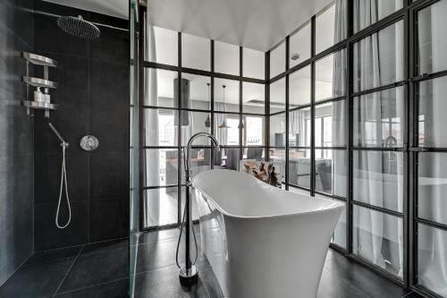 uma banheira na casa de banho com janelas de vidro em Waterlane Riverside SPA, Pool & Gym by Downtown Apartments em Gdansk