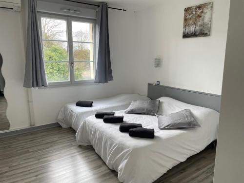 two white beds in a room with two windows at Family Hôtel FUTUROSCOPE in Jaunay-Clan