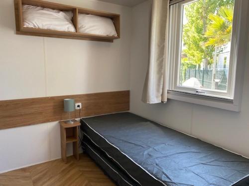łóżko w pokoju z oknem w obiekcie Mobil Home Valras Plage w mieście Valras-Plage