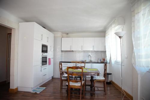 cocina con armarios blancos, mesa y sillas en Laincel - Clim - Balcon, en Arles