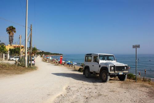a white jeep parked on a dirt road next to the beach at Villa Rosanna in Sciacca