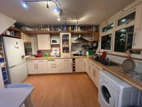 een keuken met witte kasten en een wasmachine en droger bij Arbnb Comfy Sleep Guest House Self Catering Private Bedrooms 60 pound per night per person in Londen