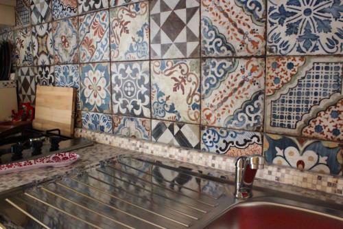 a kitchen with a sink and a tiled wall at Villa Rosanna in Sciacca