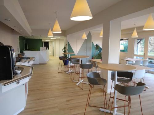 a restaurant with tables and chairs in a cafeteria at The Originals City, Hôtel Amys, Tarbes Sud in Odos
