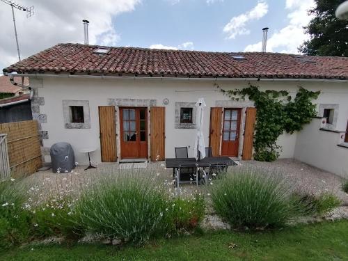 a white house with a table and chairs in the yard at La Vieille Gorce Gîtes in the Vienne in Asnois